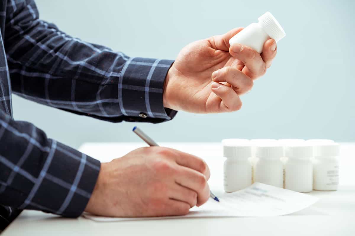 A clinical packaging technician inspecting a vial during a receipt and inspection